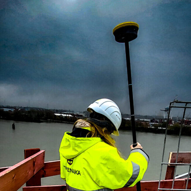 Vermesserin mit GNSS-Antenne im Sturm