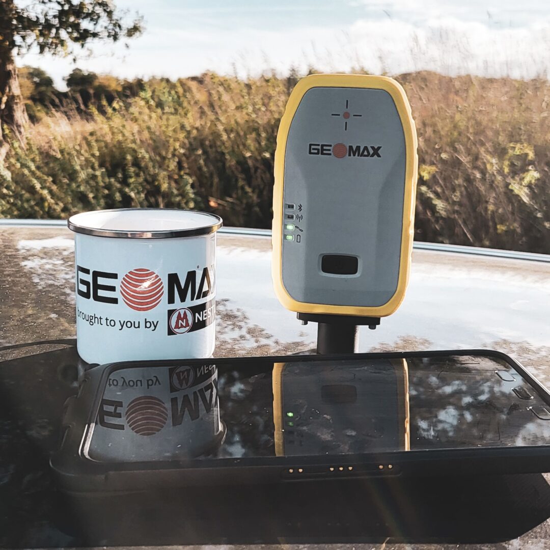 Eine GeoMax Zenith06 zu sehen neben einer Tasse, damit man die Größenverhältnisse gut erkennen kann. Die Zenith06 ist nur etwas größer als die Tasse.