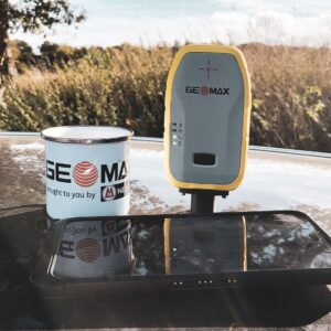 Eine GeoMax Zenith06 zu sehen neben einer Tasse, damit man die Größenverhältnisse gut erkennen kann. Die Zenith06 ist nur etwas größer als die Tasse.